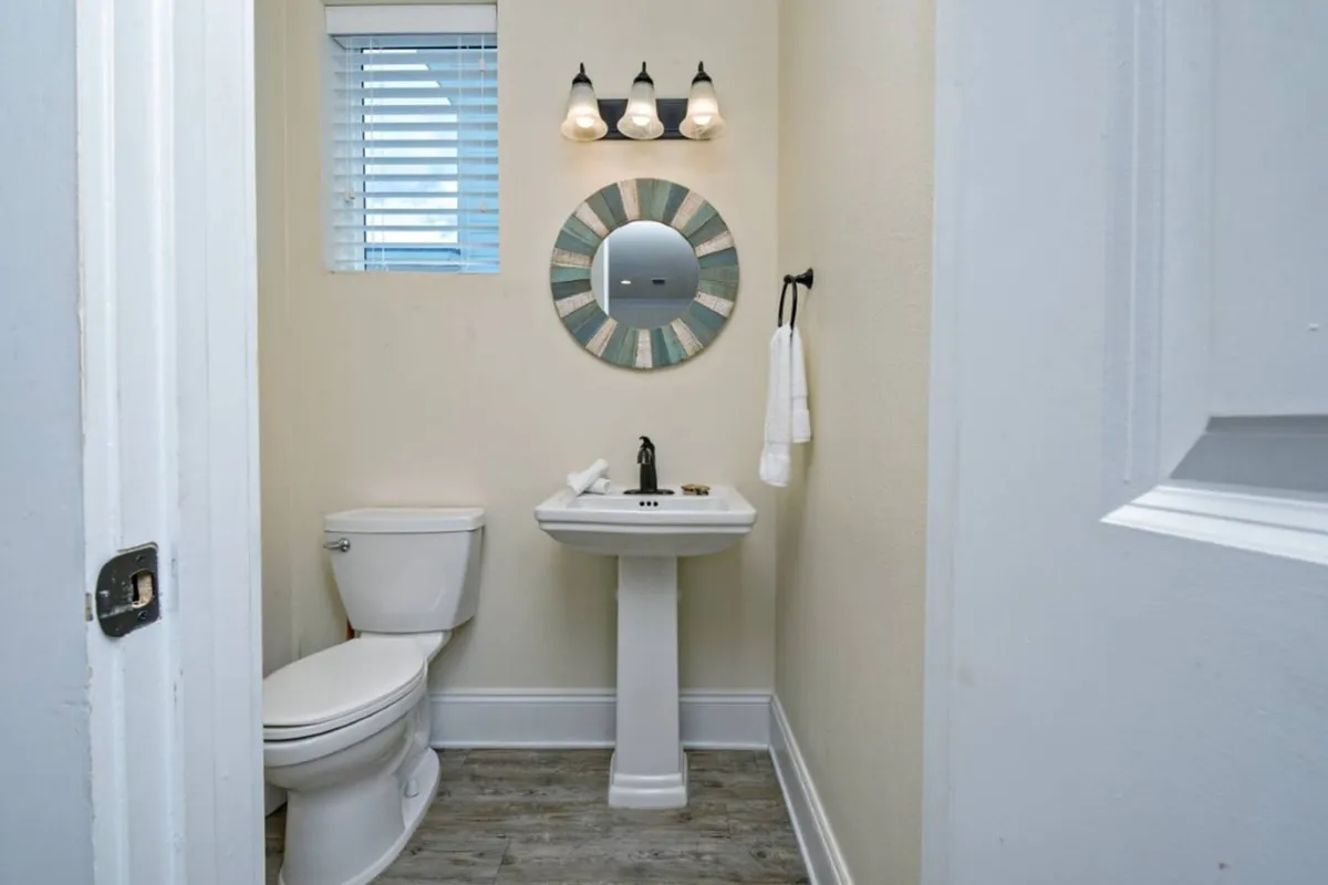 A fresh, inviting half-bath with a modern sink, mirror, and stylish lighting fixtures. Compact yet functional, the room is thoughtfully designed for quick breaks and everyday ease.