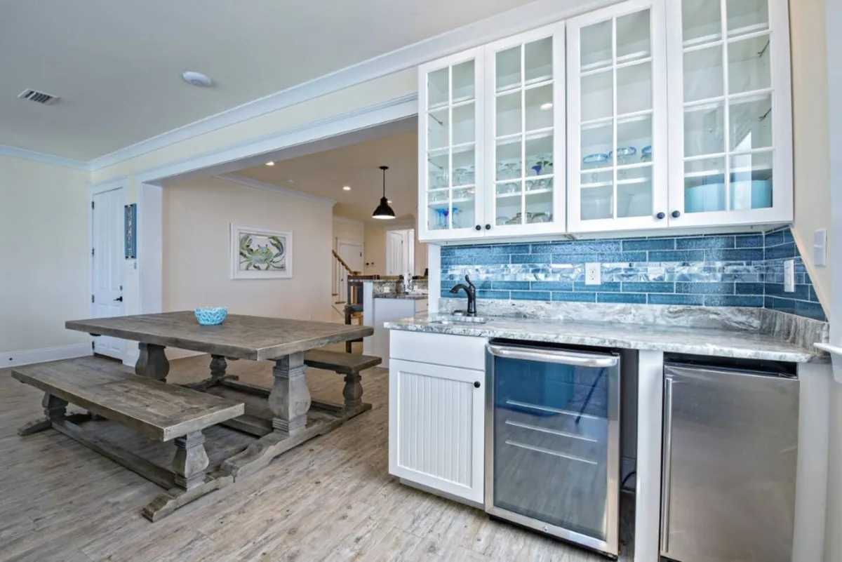 A welcoming interior space featuring a spacious kitchen island, blue tile backsplash, and a roomy wooden dining table. The setup encourages preparing meals together, sharing stories, and hosting group feasts after a day of exploring the area.