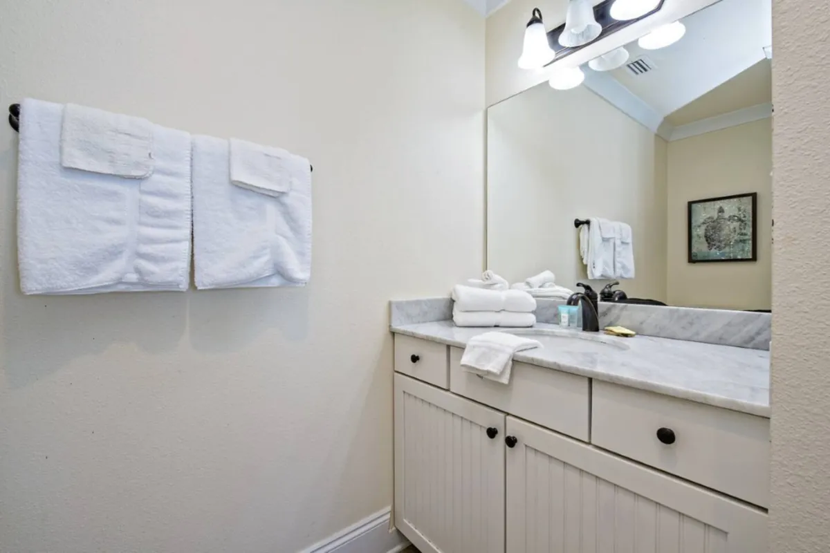 A serene bathroom scene highlighting marble countertops, plush towels, a mirror, and a sparkling sink. The atmosphere is clean and relaxing, suggesting a spa-like quality for daily routines.